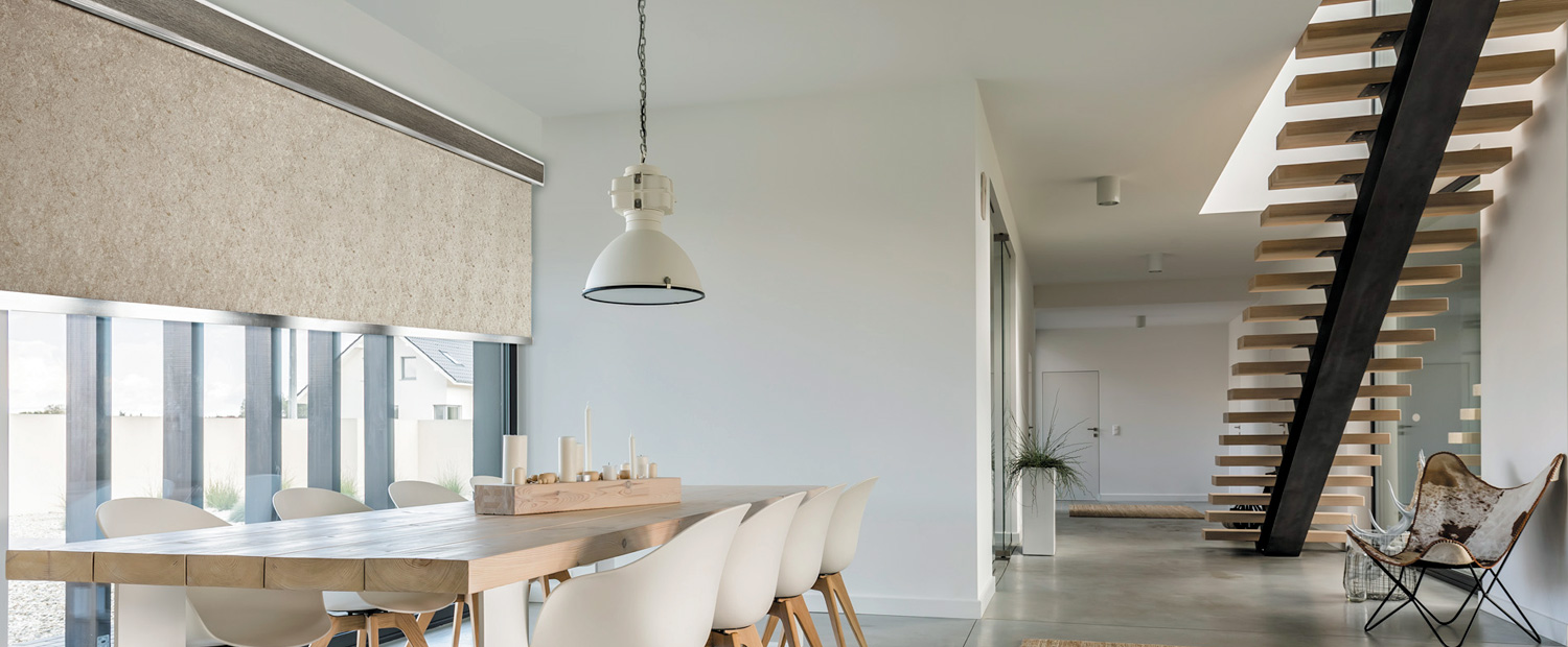 Wide decorative roller shade with valance in private residence 8 chair dining area, modern architecture.